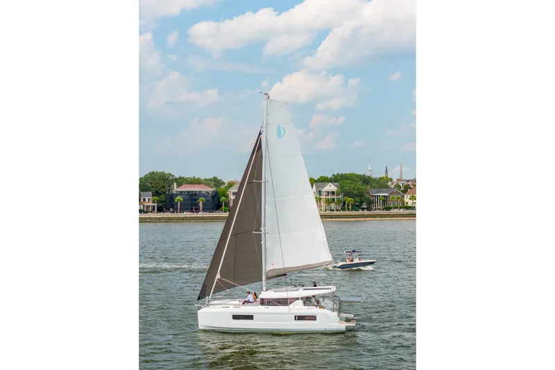 Slide: The Image of 2026 Lagoon 38 sailboat cruising on a scenic waterway under a partly cloudy sky. - 105
