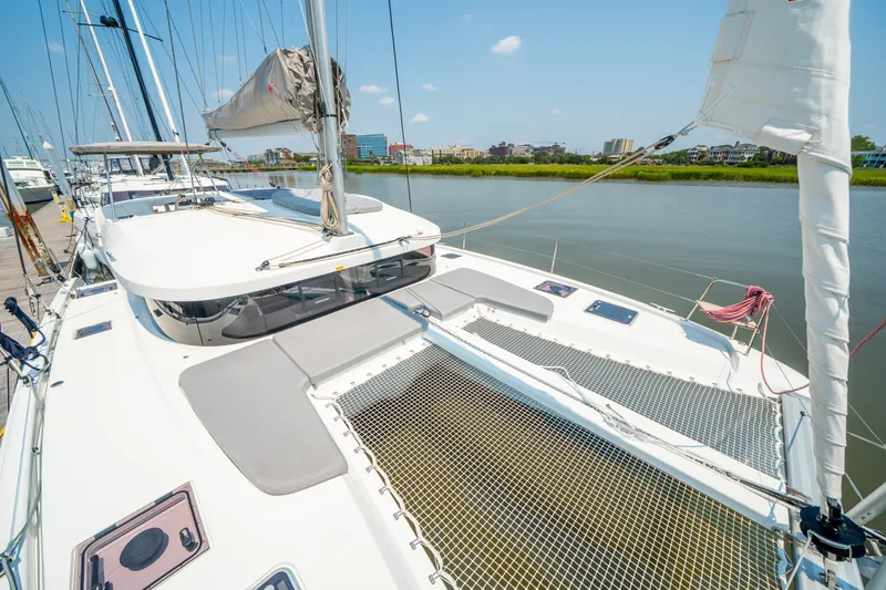 Slide: The Image of 2026 Lagoon 38 catamaran docked by a calm river under clear blue skies. - 13