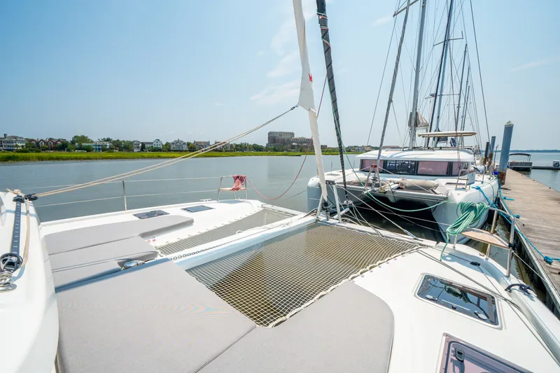 Slide: The Image of 2026 Lagoon 38 catamaran docked by a serene waterfront on a sunny day. - 12