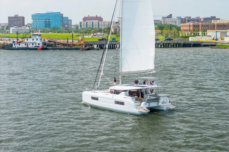 Slide: The Image of 2026 Lagoon 38 catamaran sailing near urban waterfront with buildings in background. - 107