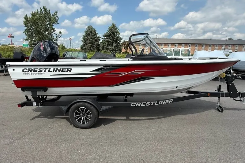 The Image of 2027 Crestliner 1850 Sportfish boat on trailer, red and white design, parked outdoors. - 0