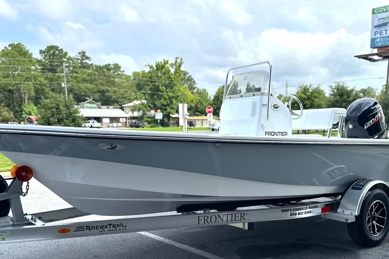 Slide: The Image of 2027 Frontier 180 boat on trailer, parked outdoors with trees in background. - 1