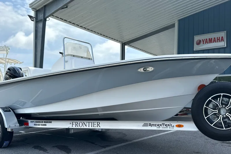 Slide: The Image of 2027 Frontier 180 boat on trailer, parked under a canopy near Yamaha sign. - 18