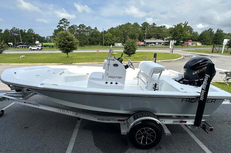 Slide: The Image of 2027 Frontier 180 boat on trailer, parked outdoors, with trees and road in background. - 9