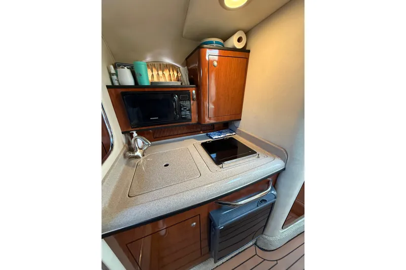 Slide: The Image of 2007 Sea Ray 340 yacht kitchen with microwave, sink, and wooden cabinetry. - 18