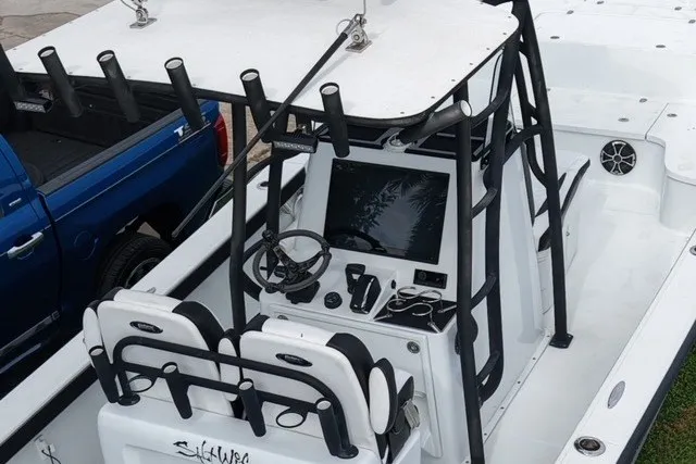 Slide: The Image of 2023 Canyon Bay 28h boat interior with steering console and seating, parked beside a blue truck. - 3