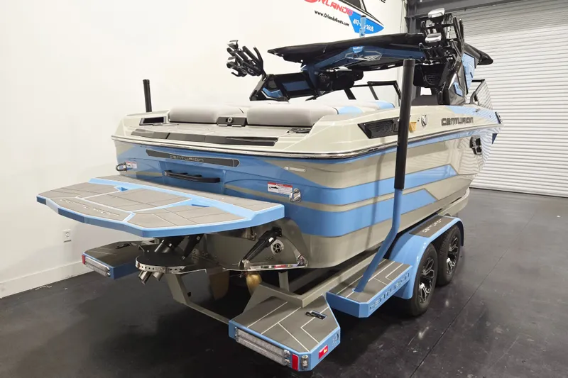 Slide: The Image of 2026 Centurion Ri230 boat in showroom, featuring sleek design and dual-axle trailer. - 4
