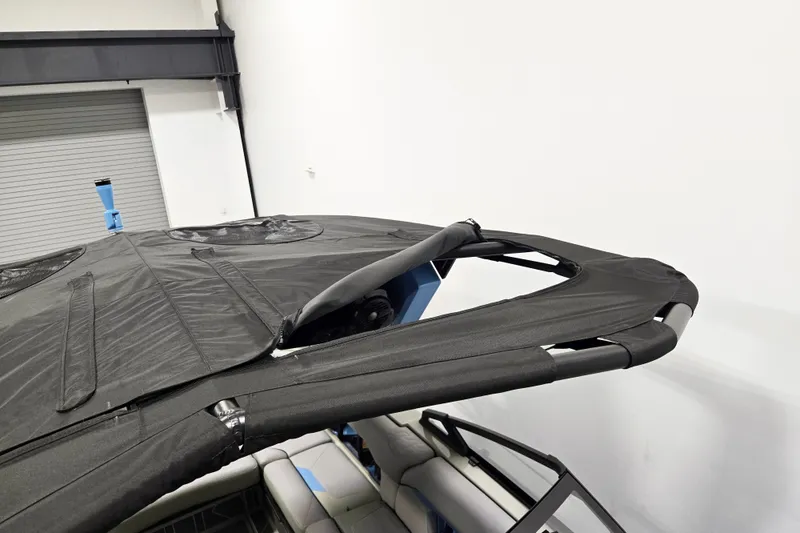 Slide: The Image of 2026 Centurion Ri230 boat with a sleek black canopy in a showroom setting. - 16