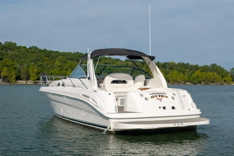 Slide: The Image of 2000 Sea Ray 410 Sundancer yacht on a serene lake with lush green shoreline. - 9