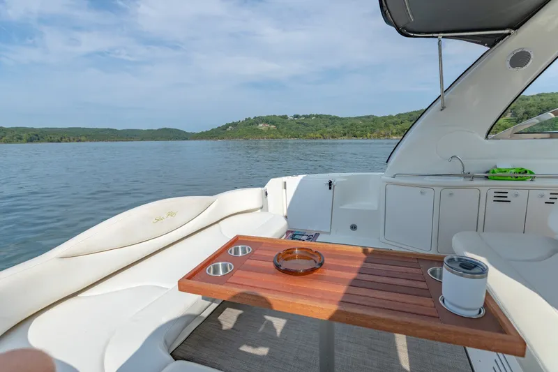 Slide: The Image of 2000 Sea Ray 410 Sundancer yacht interior with wooden table, lake view, and lush green hills. - 17