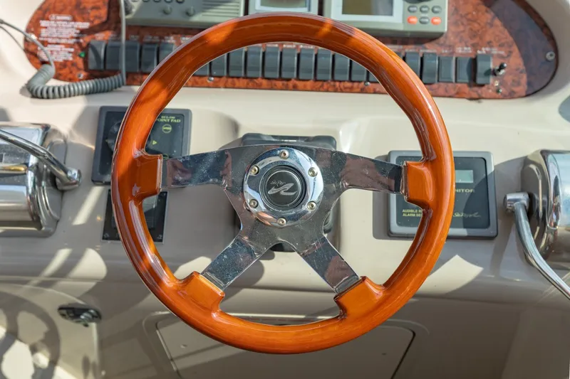 Slide: The Image of Steering wheel of a 2000 Sea Ray 410 Sundancer boat, featuring wood and chrome accents. - 33