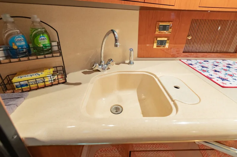 Slide: The Image of Kitchen sink area in a 2000 Sea Ray 410 Sundancer yacht with cleaning supplies. - 49
