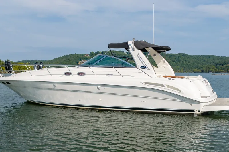 Slide: The Image of 2000 Sea Ray 410 Sundancer yacht on a serene lake with lush green hills. - 8