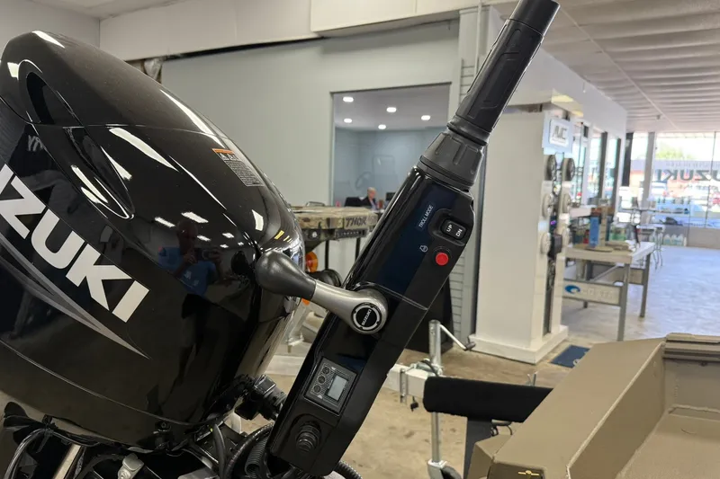 Slide: The Image of Outboard motor with control handle, featuring Suzuki branding, in a showroom setting. - 12