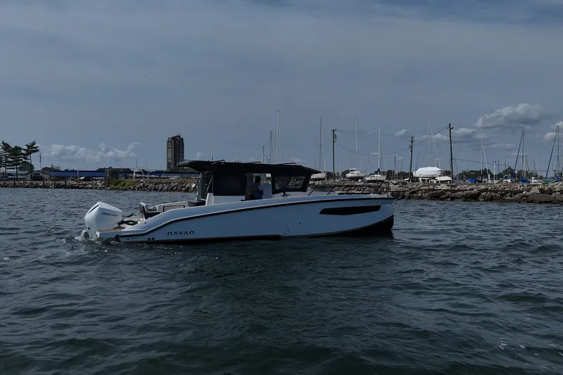 Slide: The Image of Navan C30 2026 boat cruising near marina with sailboats and cityscape in background. - 7