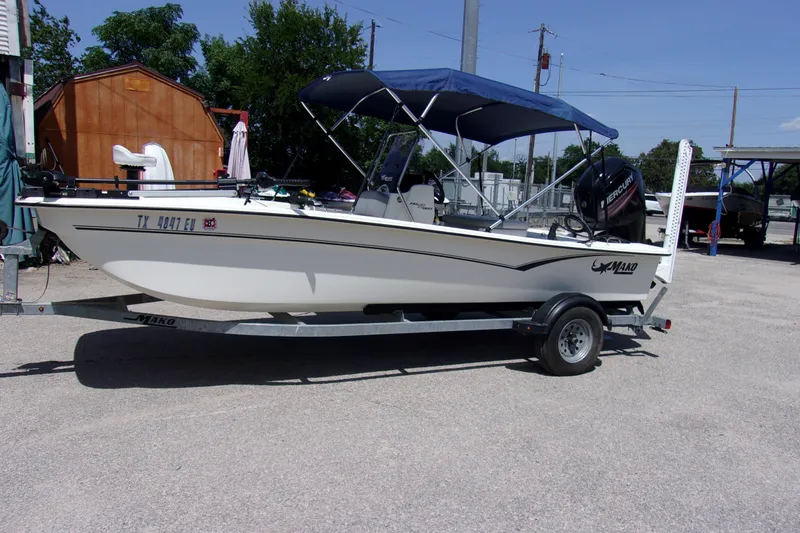 The Image of 2019 Mako Pro Skiff 17 CC boat on trailer with blue canopy in outdoor setting. - 1