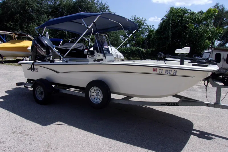 Slide: The Image of 2019 Mako Pro Skiff 17 CC boat on trailer with canopy in outdoor setting. - 2