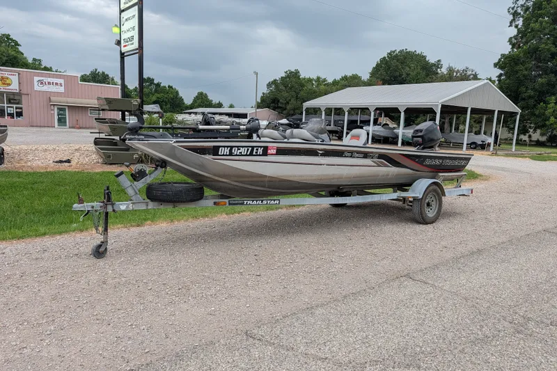 The Image of 1999 Tracker Pro Team 175 boat on trailer, parked outdoors near dealership. - 1