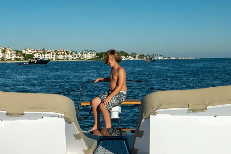 Slide: The Image of Boy enjoying a sunny day on a Hanover 375 yacht, 2026 model, near coastal buildings. - 49
