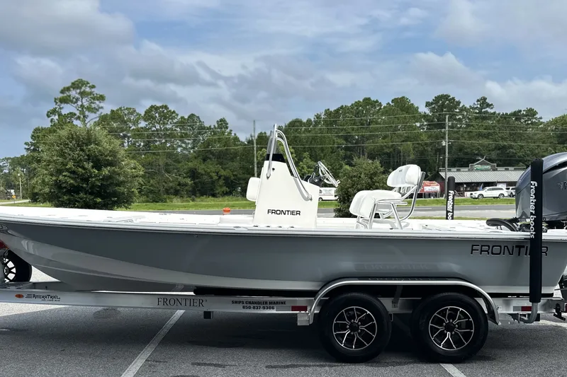 Slide: The Image of 2027 Frontier 2104 boat on trailer, parked outdoors with trees in background. - 23