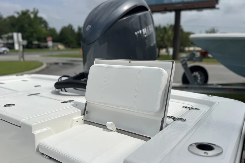 Slide: The Image of 2027 Frontier 2104 boat with white seating and outboard motor in a parking area. - 14