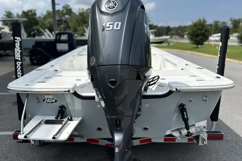 Slide: The Image of 2027 Frontier 2104 boat with Yamaha 150 outboard motor, parked outdoors. - 27