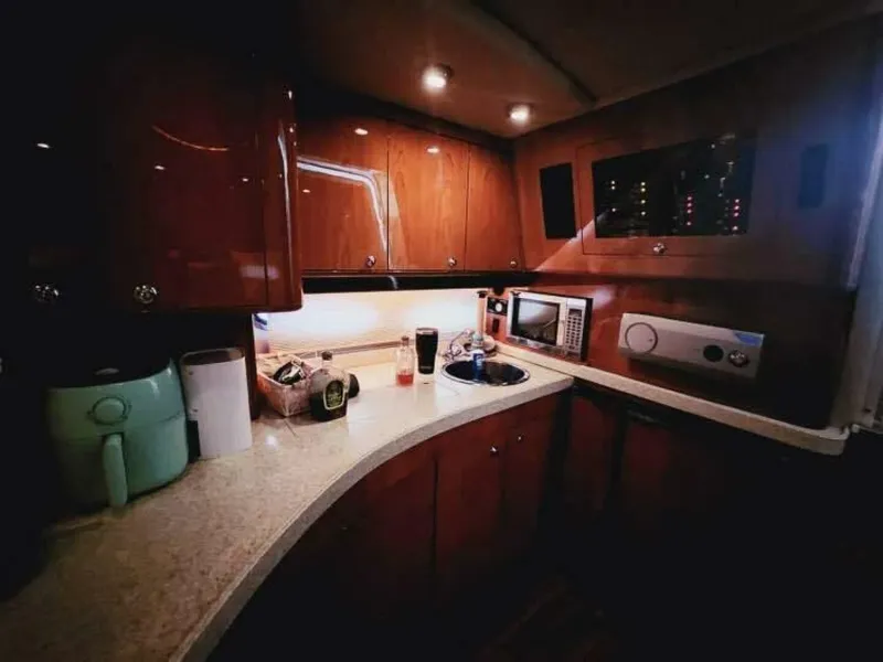 Slide: The Image of The 2007 Regal Commodore 4460's galley features elegant wood cabinets, a sink, and modern appliances. - 10