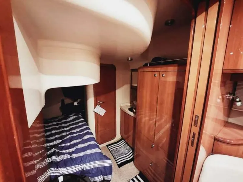 Slide: The Image of The 2007 Regal Commodore 4460 cabin features a cozy bed, wooden cabinetry, and carpeting. - 18
