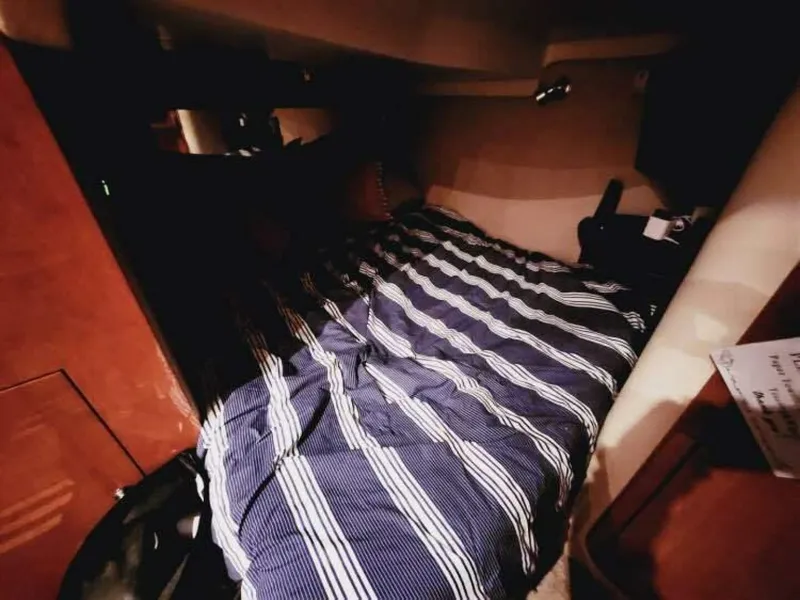 Slide: The Image of A cozy cabin with a striped bedspread in a Regal Commodore 4460 boat. - 16