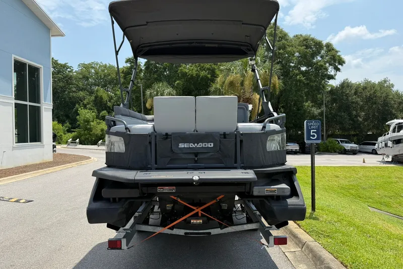 Slide: The Image of 2023 Sea-Doo Switch Sport 21 pontoon boat parked on a sunny street. - 2