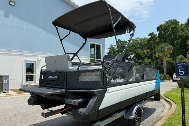 Slide: The Image of 2023 Sea-Doo Switch Sport 21 pontoon boat parked outdoors near a building. - 3