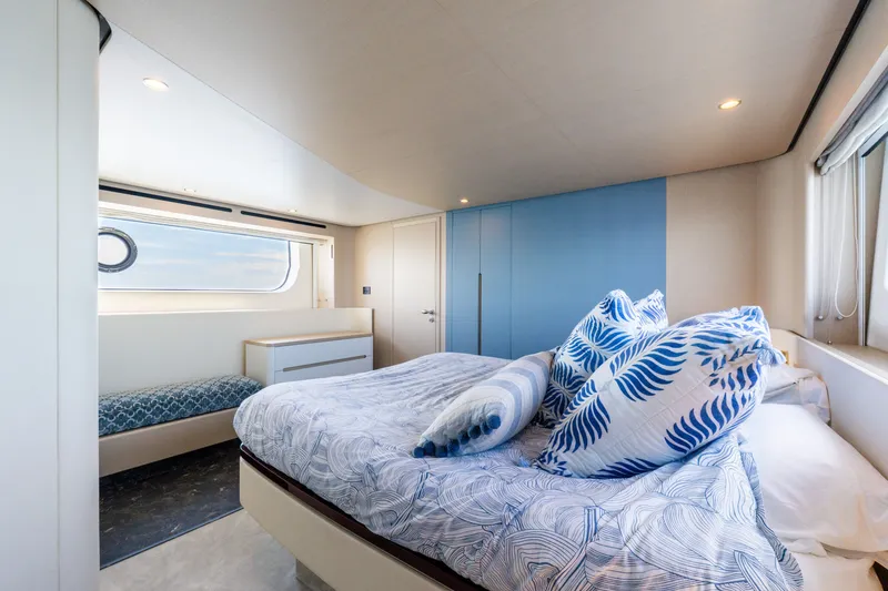 Slide: The Image of The image shows a luxurious cabin with a large bed, blue pillows, and a window. - 33
