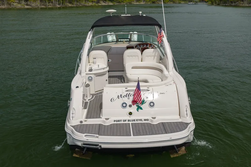Slide: The Image of 2004 Sea Ray 340 Sundancer boat on water, rear view with American flags. - 11