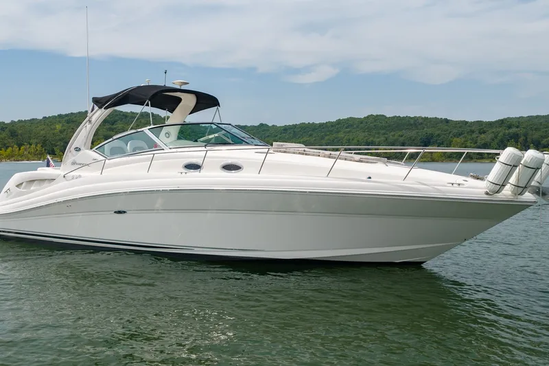 Slide: The Image of 2004 Sea Ray 340 Sundancer yacht on a serene lake with lush green shoreline. - 3