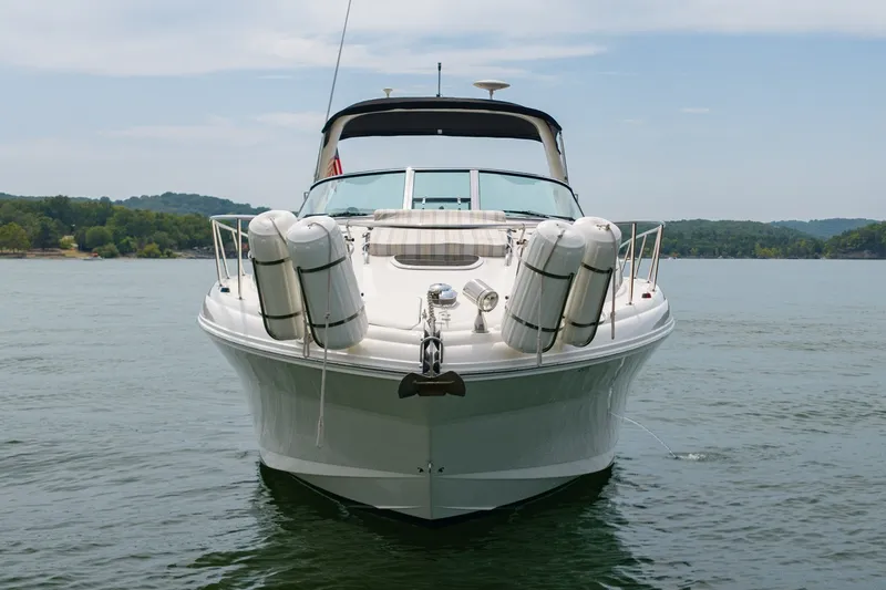 Slide: The Image of 2004 Sea Ray 340 Sundancer yacht on calm water, front view with scenic background. - 6