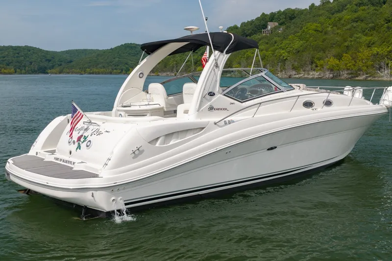 Slide: The Image of 2004 Sea Ray 340 Sundancer boat on a lake, surrounded by lush green hills. - 2