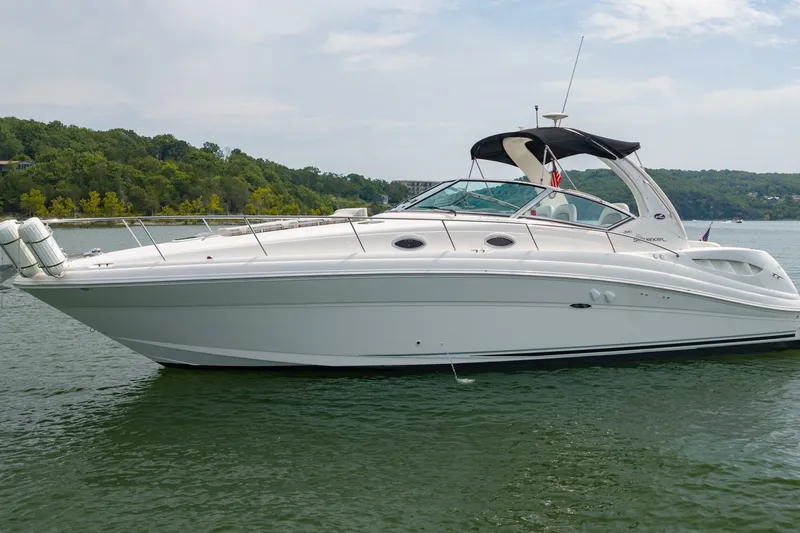 Slide: The Image of 2004 Sea Ray 340 Sundancer yacht on calm water, surrounded by lush greenery. - 13