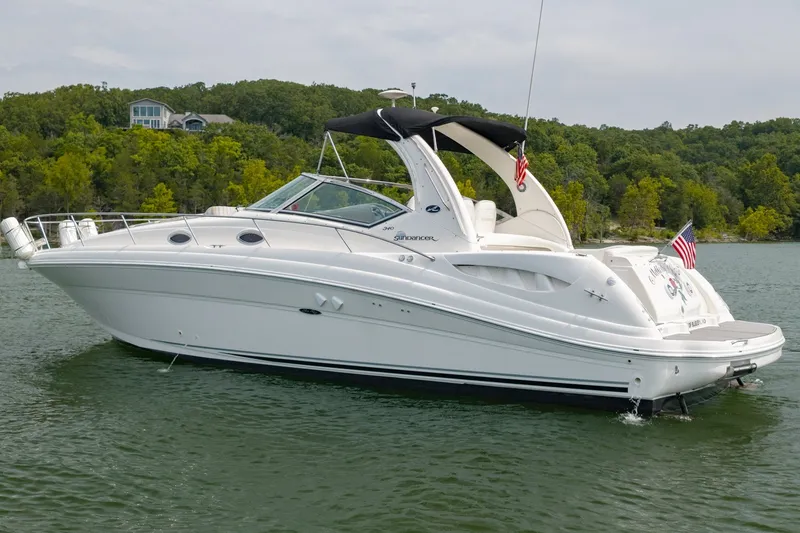 Slide: The Image of 2004 Sea Ray 340 Sundancer yacht on a serene lake with lush green shoreline. - 8