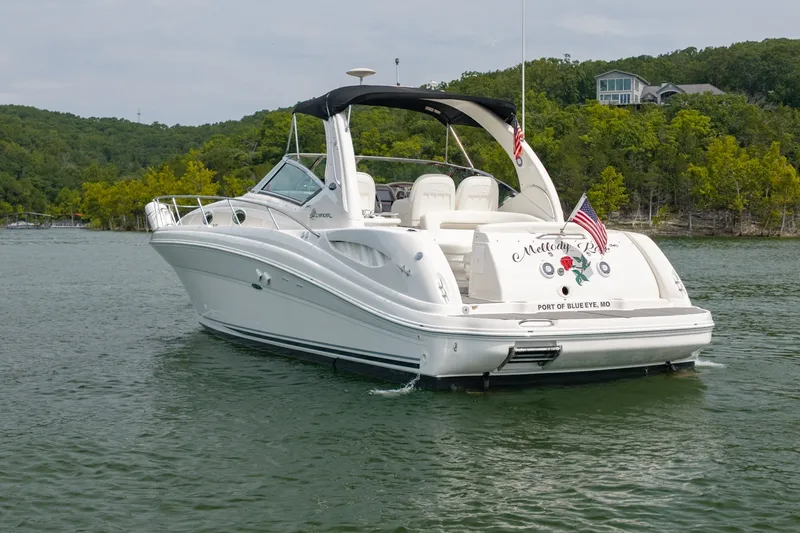 Slide: The Image of 2004 Sea Ray 340 Sundancer yacht on a serene lake with lush green shoreline. - 5