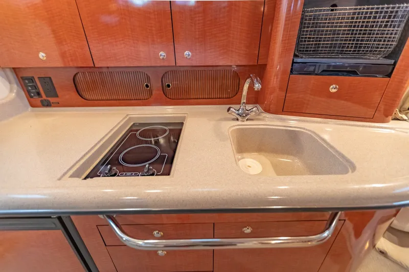Slide: The Image of 2004 Sea Ray 340 Sundancer galley with stove, sink, and wooden cabinetry. - 36