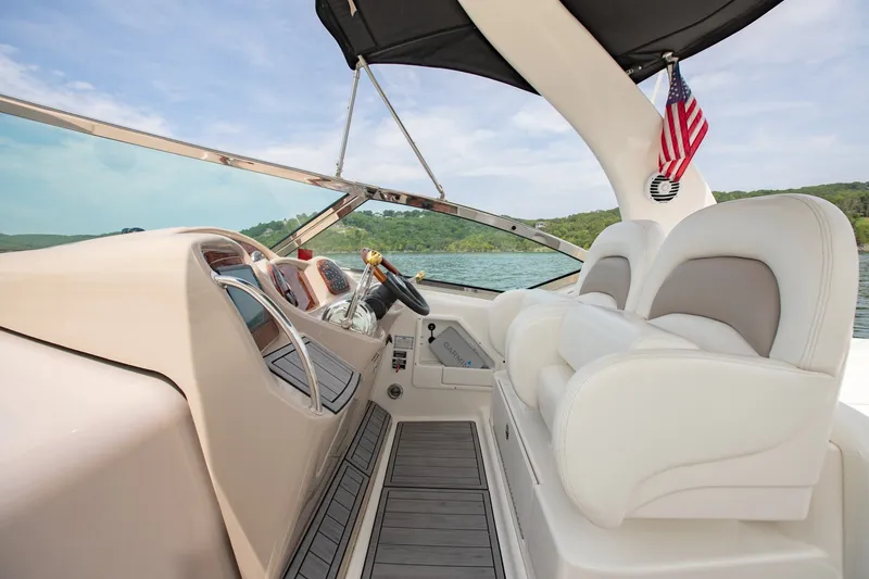 Slide: The Image of 2004 Sea Ray 340 Sundancer cockpit with white seating and American flag on a sunny day. - 21