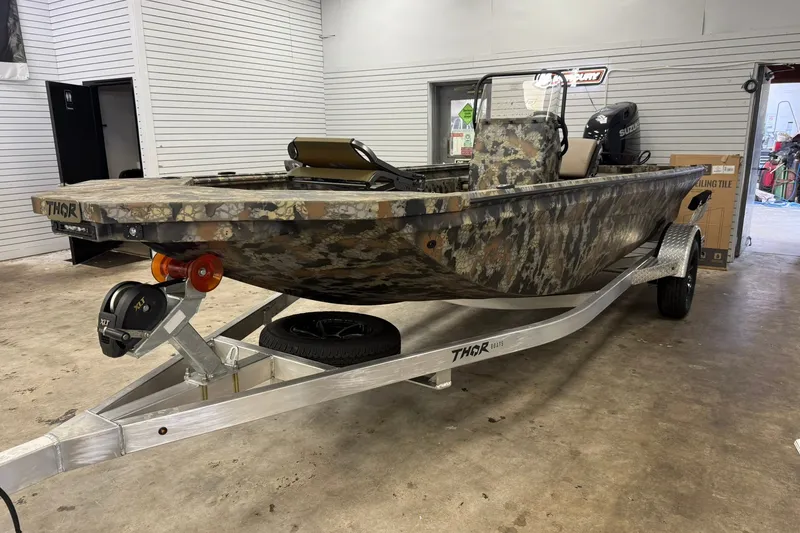 Slide: The Image of 2027 Thor BH1900CC camo boat on trailer in showroom, featuring Suzuki outboard motor. - 3