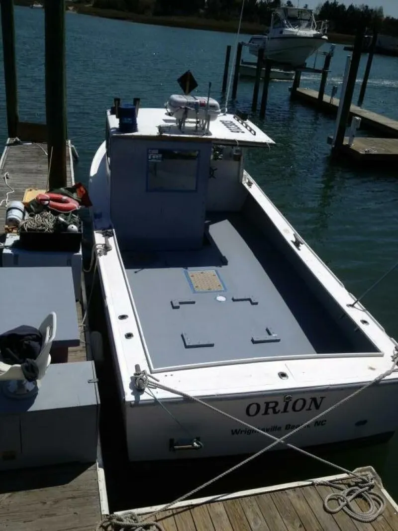 Slide: The Image of A 1986 BHM 32 boat docked at a pier. It features an open deck area and is moored in a calm harbor. - 4