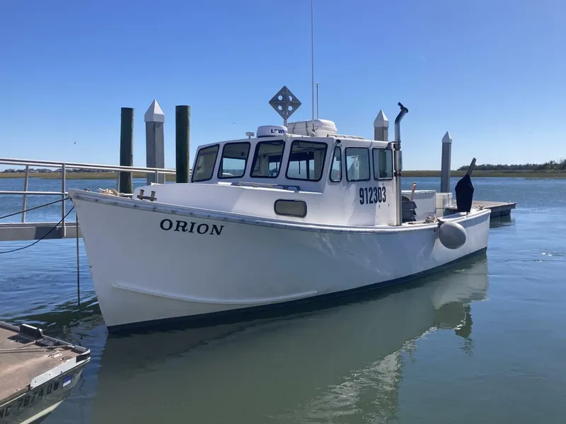 Slide: The Image of A white boat named "ORION" is docked. It features a cabin and a registration number. - 1