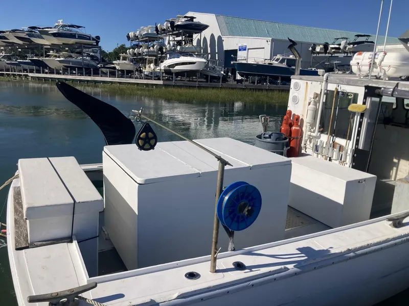 Slide: The Image of A 1986 BHM 32 boat is in the water. It features an open work area and is docked in a marina with several boats in the background. - 13