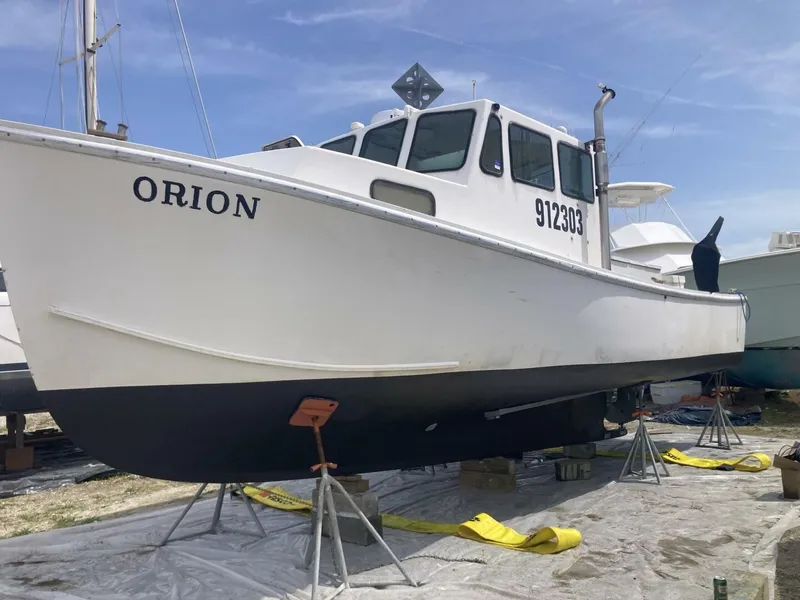 Slide: The Image of A white boat named "ORION" is on stands on land. It has a sturdy build. - 34