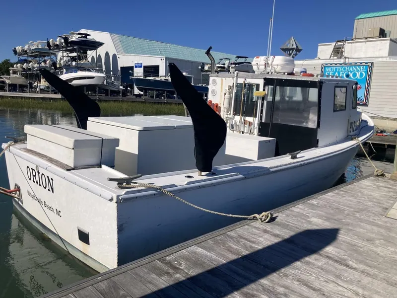 Slide: The Image of A 1986 BHM 32 boat docked. It features a white hull and cabin. - 28