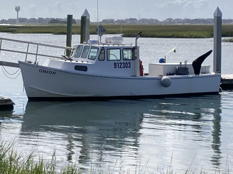 Slide: The Image of A white fishing boat named "ORION" is docked in calm waters. - 33