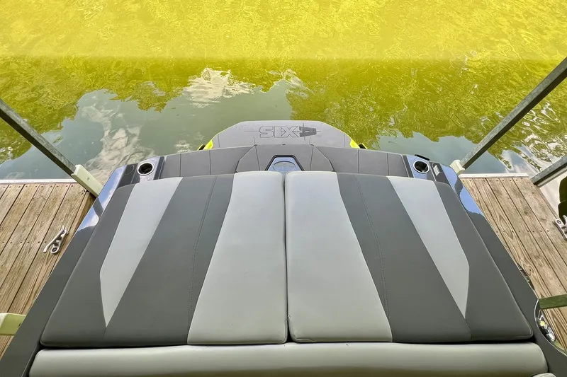 Slide: The Image of Rear view of 2023 Axis A225 boat with cushioned seating and lake backdrop. - 9