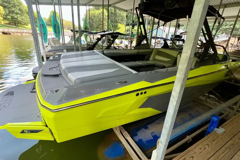 Slide: The Image of 2023 Axis A225 boat in vibrant yellow docked at a marina. - 2